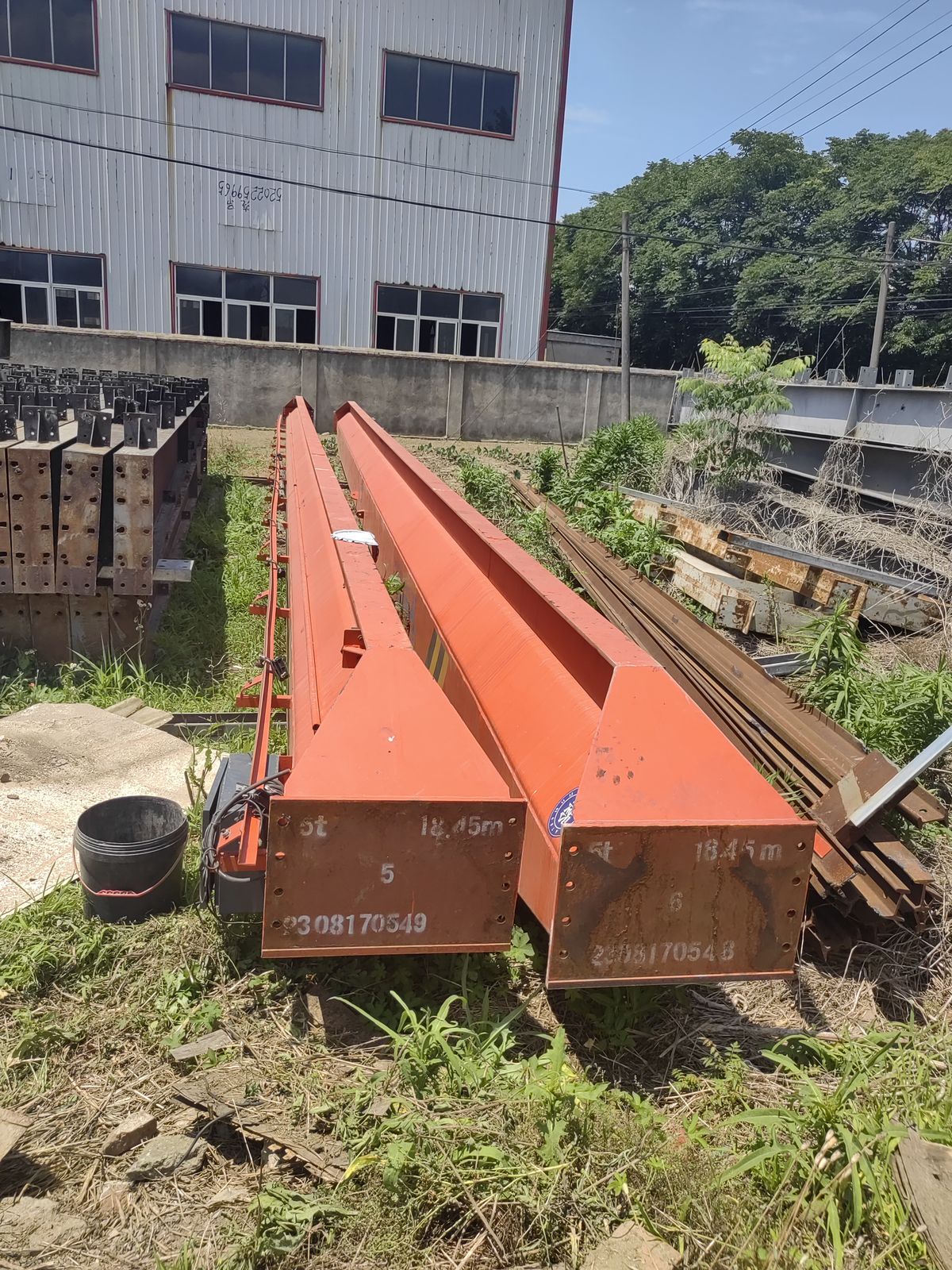 两根拆下来的红丹漆焊接H型钢梁，整根码放在货场